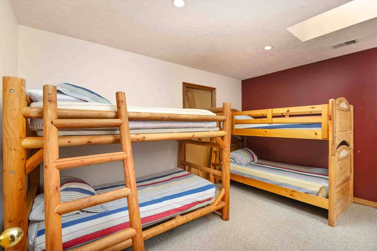 A cozy room with playful bunk beds dressed in striped bedding and surrounded by wooden furniture. The setup is ideal for children or multiple guests, evoking memories of sleepovers and late-night storytelling.